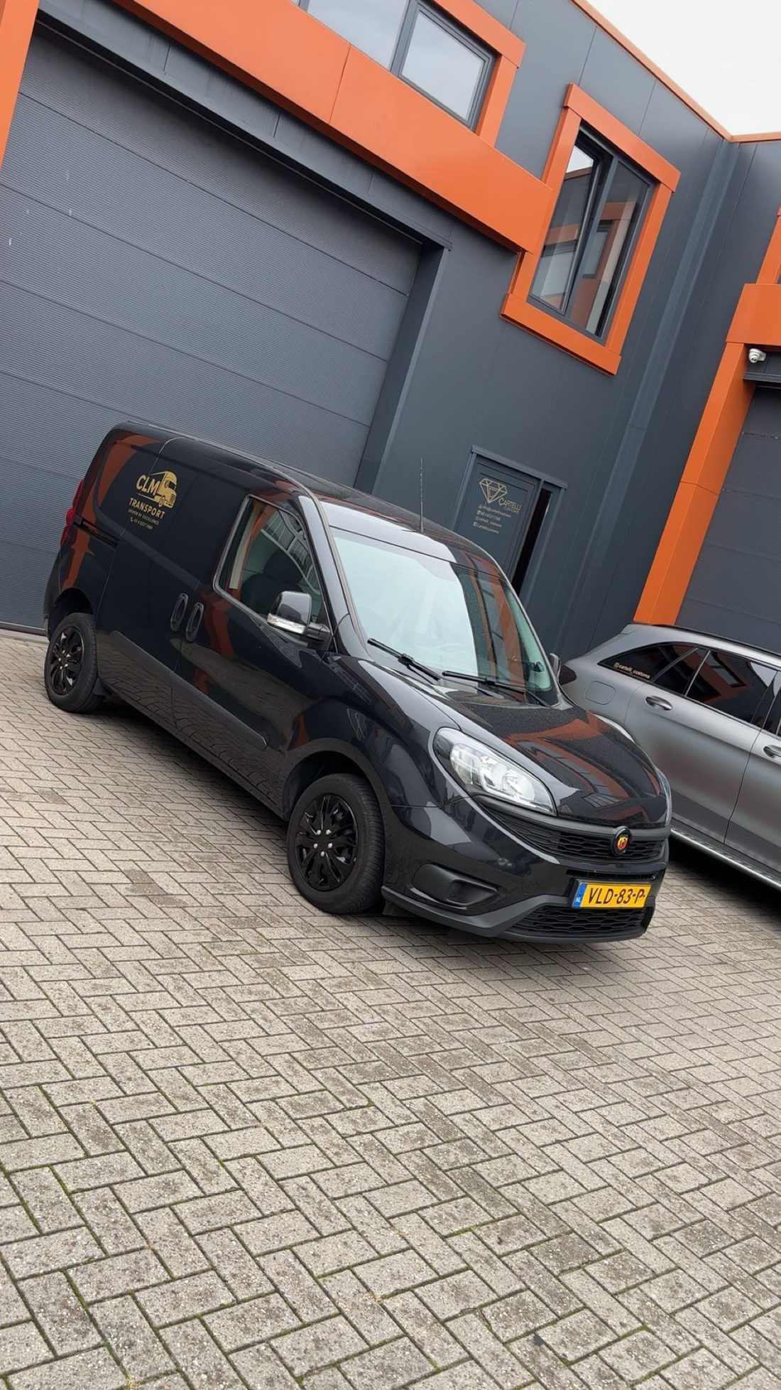 De zwarte Fiat Doblò van CLM Transport met goudkleurig bedrijfslogo